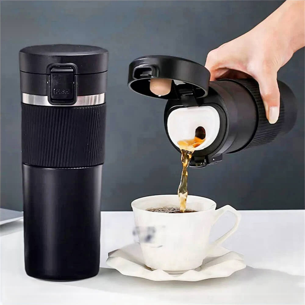 Black 20 oz stainless steel tumbler with a flip-top lid pouring hot coffee into a white ceramic cup, shown on a white table with another closed tumbler beside it.