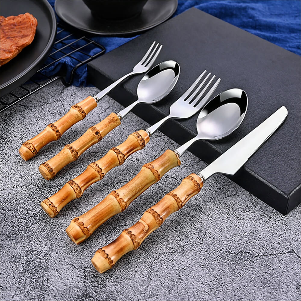 A 5-piece stainless steel flatware set with natural bamboo-style handles displayed on a textured gray surface.
