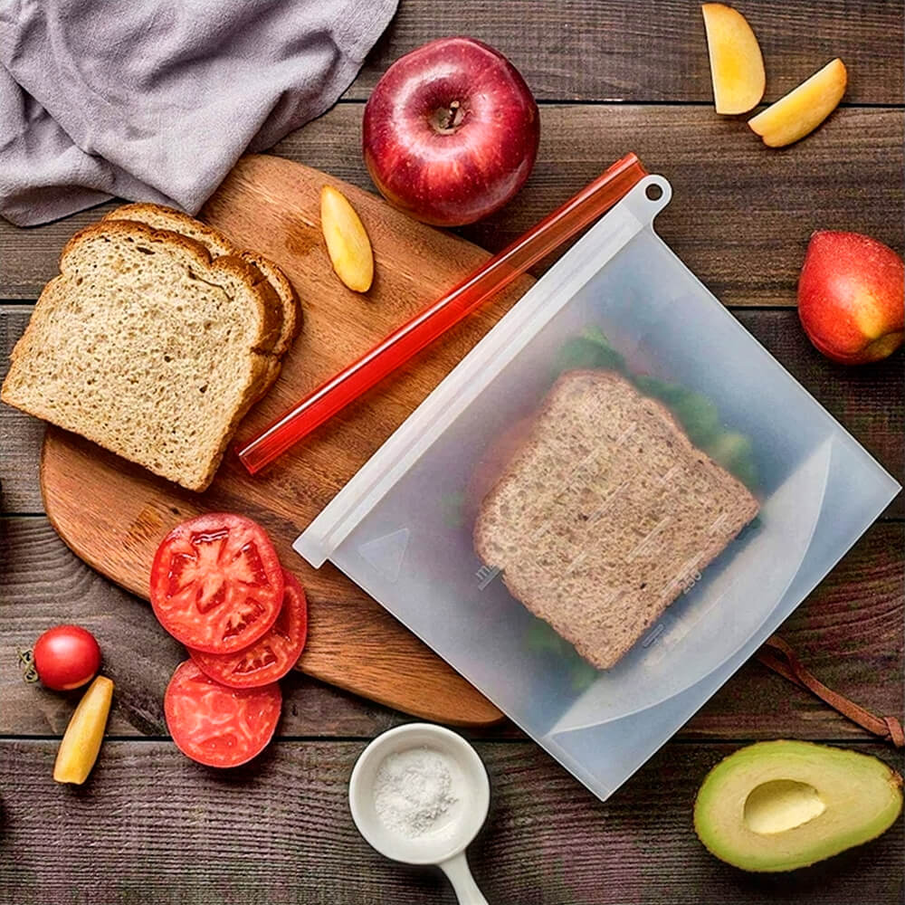 Sandwich stored in one of the best reusable silicone bags, placed on a wooden surface with fresh ingredients around.