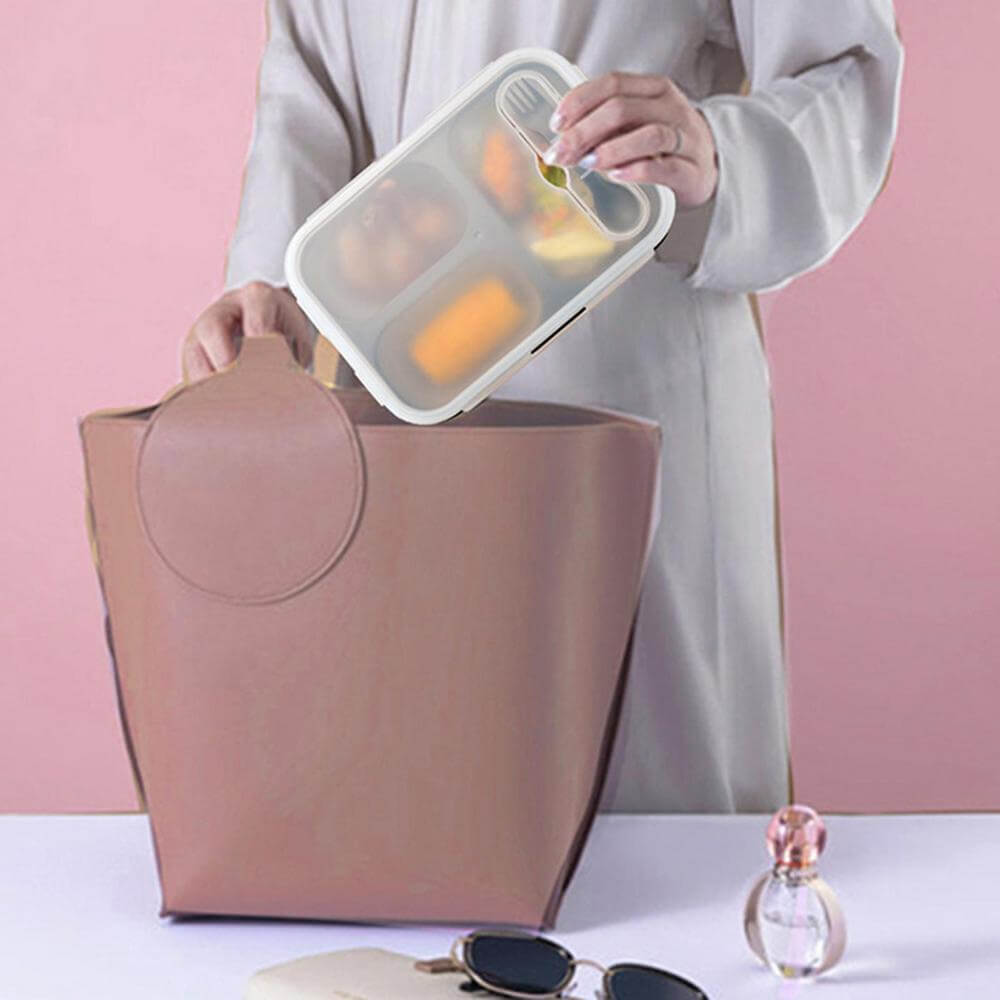 Person placing a collapsible silicone lunch box with compartments into a beige tote bag, ideal for meals on the go.