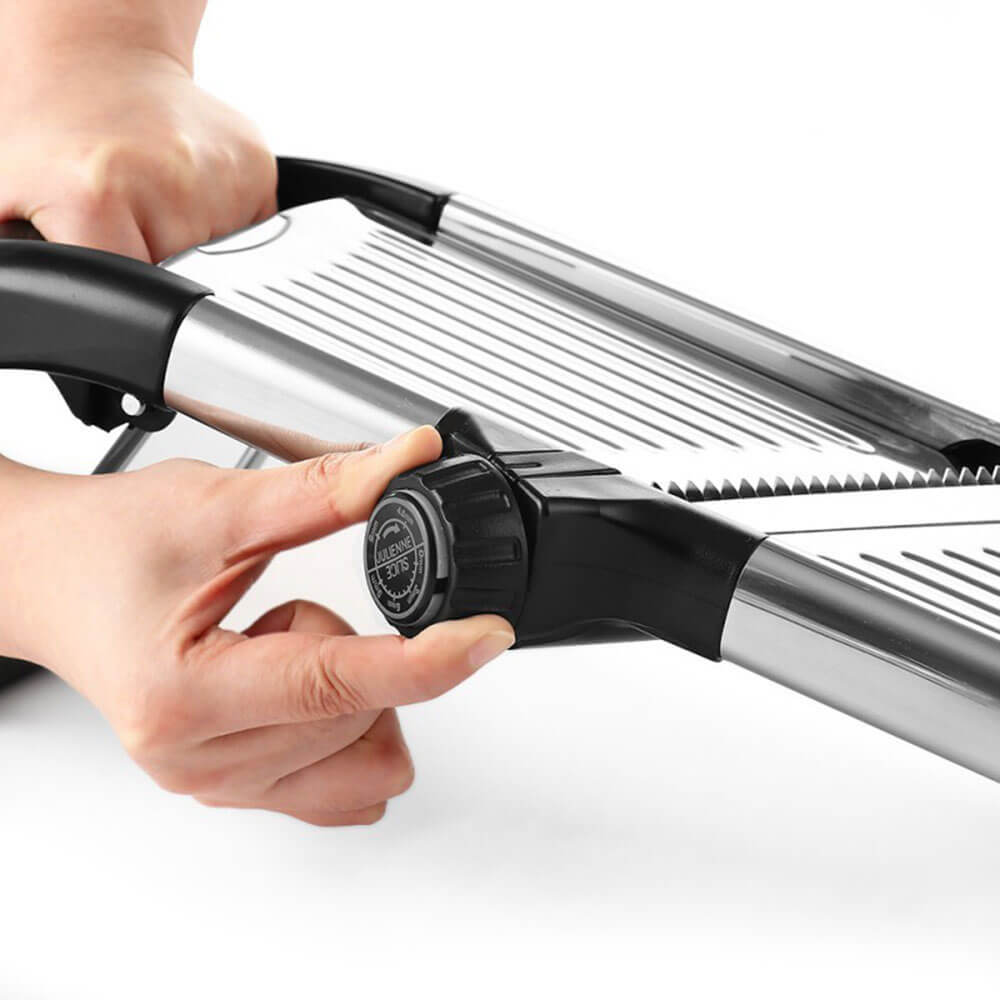 Cooking mandoline slicer being adjusted for precise thickness, featuring sharp blades and safety knob.