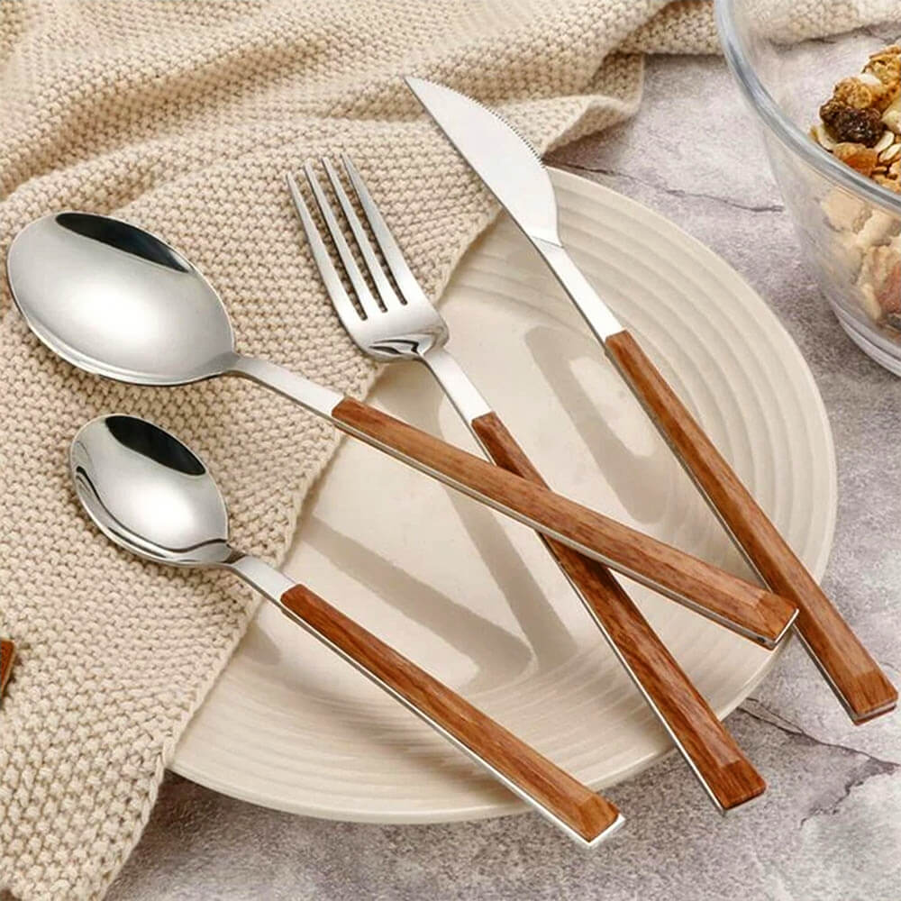 Four-piece flatware with wooden handles set on a cream plate and knitted beige cloth next to a bowl of cereal.