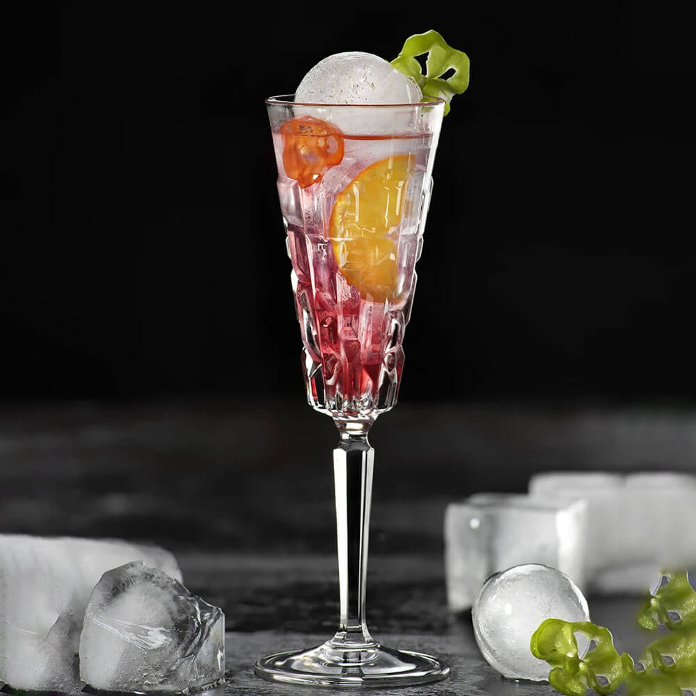 Elegant crystal flutes glasses filled with fruit cocktail and ice, perfect for champagne or sparkling drinks.