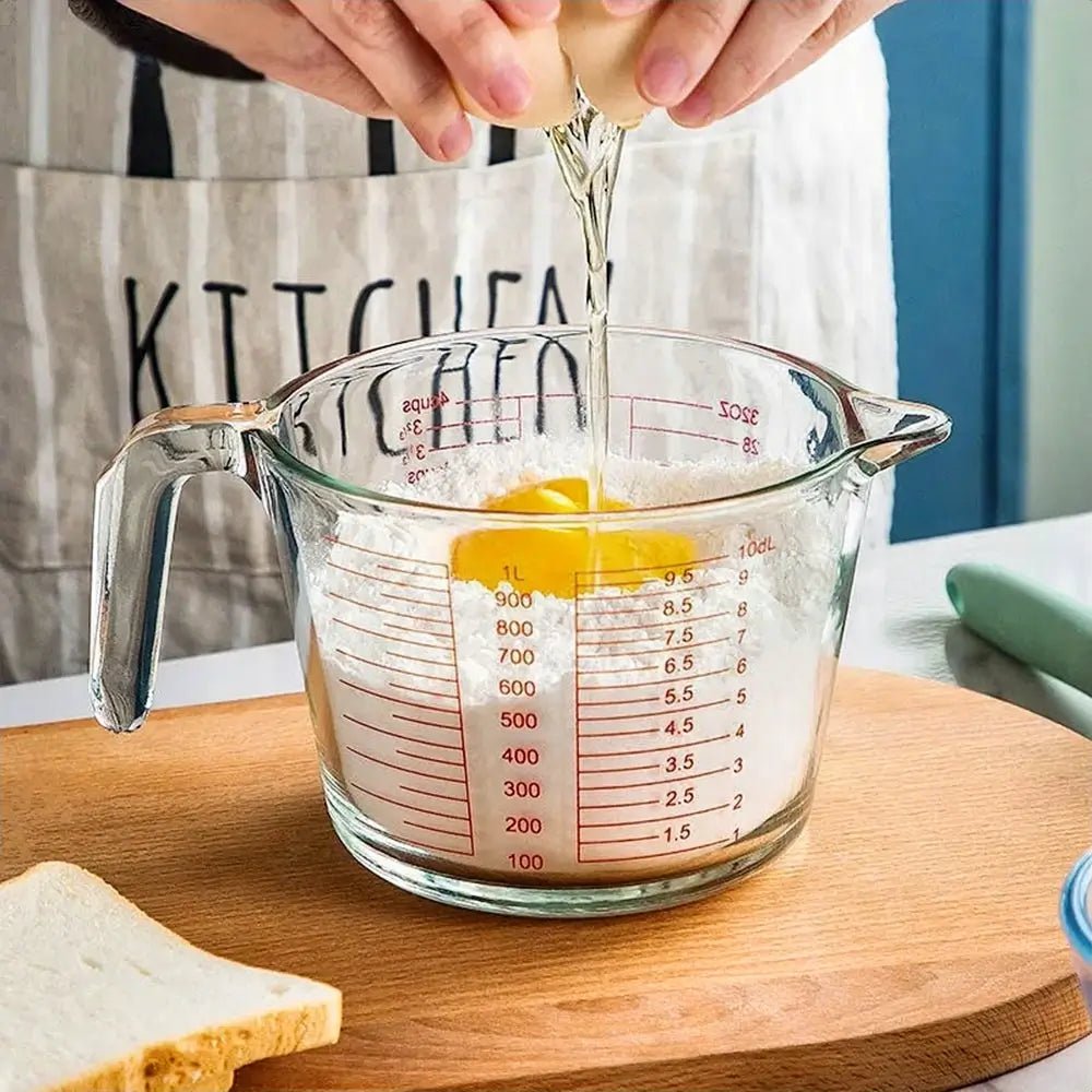 Person cracking an egg into flour inside a glass measuring cup Pyrex, showcasing precise measurements for accurate baking preparation.