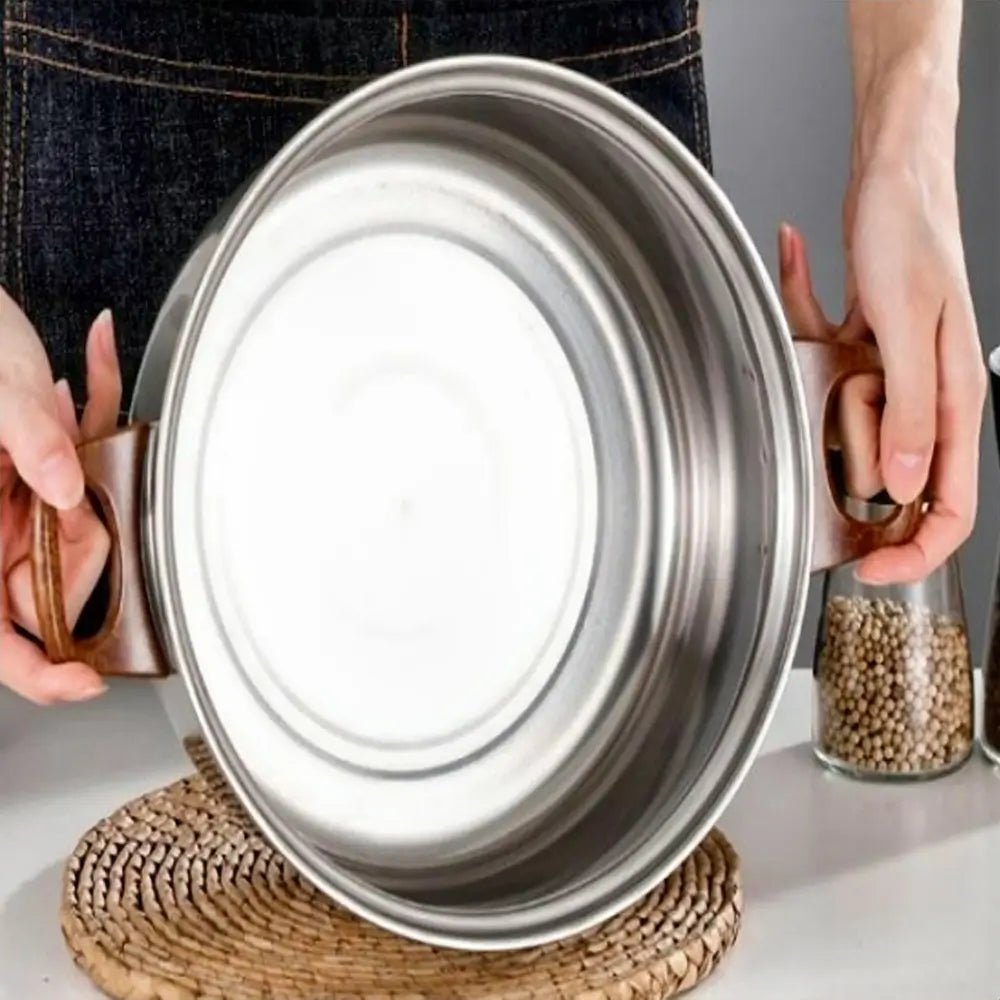 Non stick stainless steel cookware sets pot held over table mat, showing bottom design and wooden side handles.