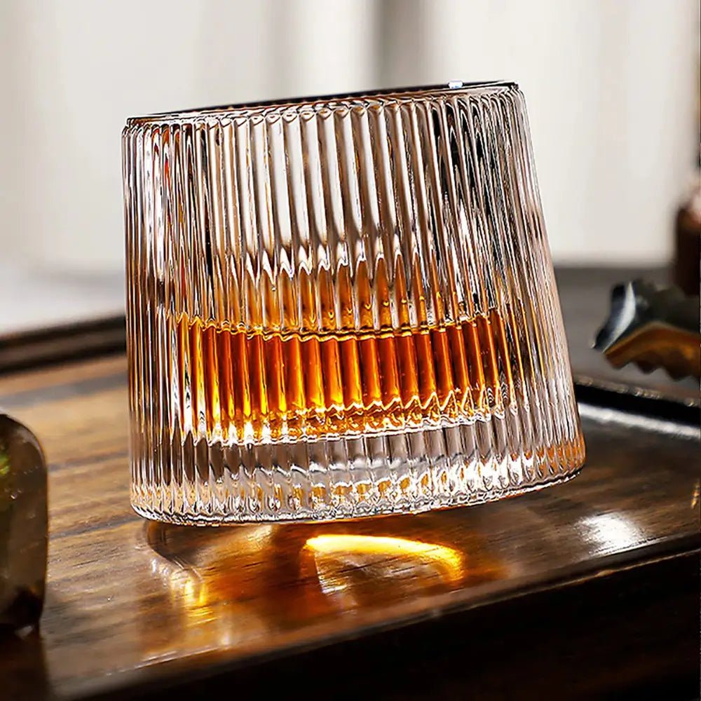Ribbed-glasses tumbler with vertical ridges holding amber liquid on a wooden surface with light reflections.