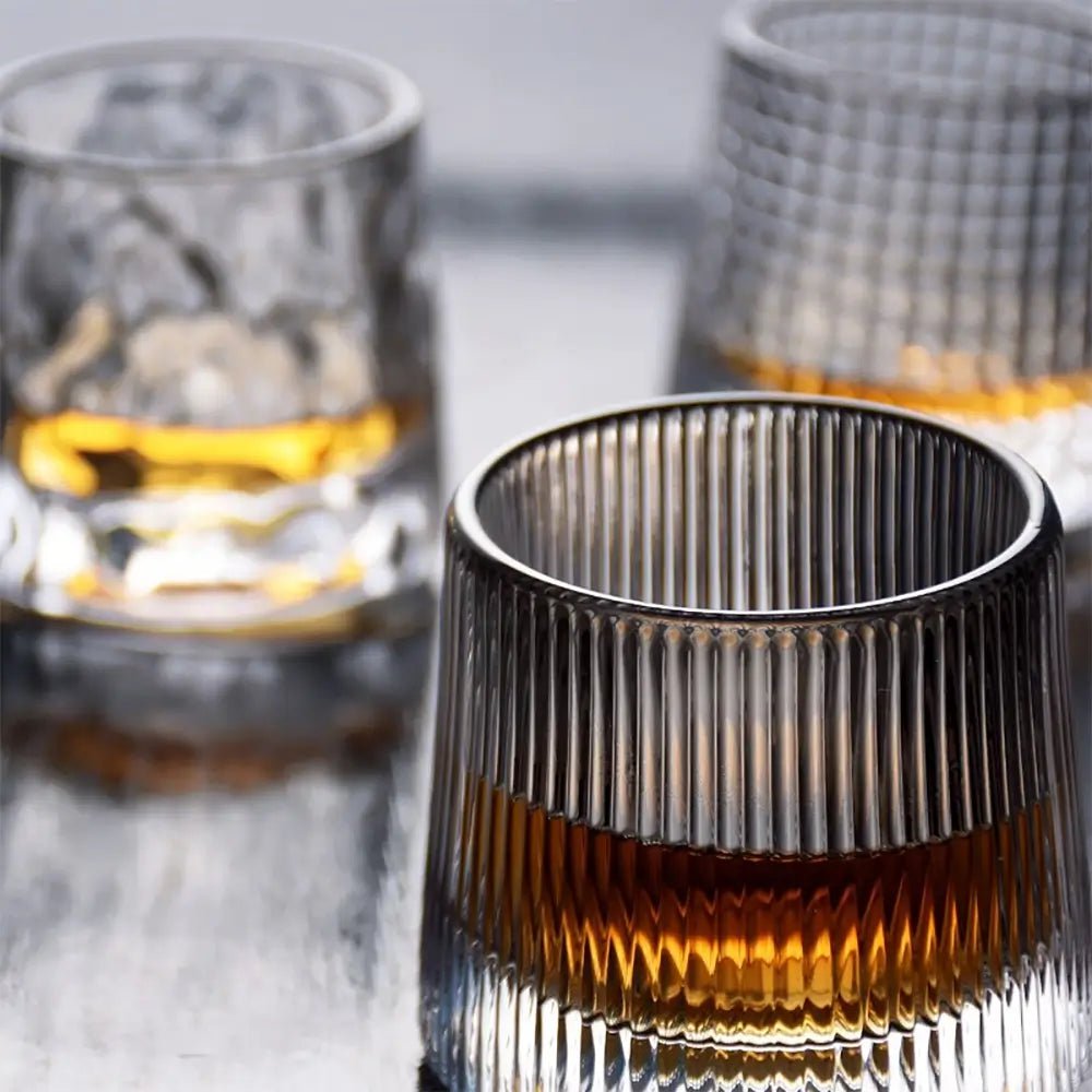 Ribbed-wine-glasses with vertical ridges holding amber liquid on a reflective surface.
