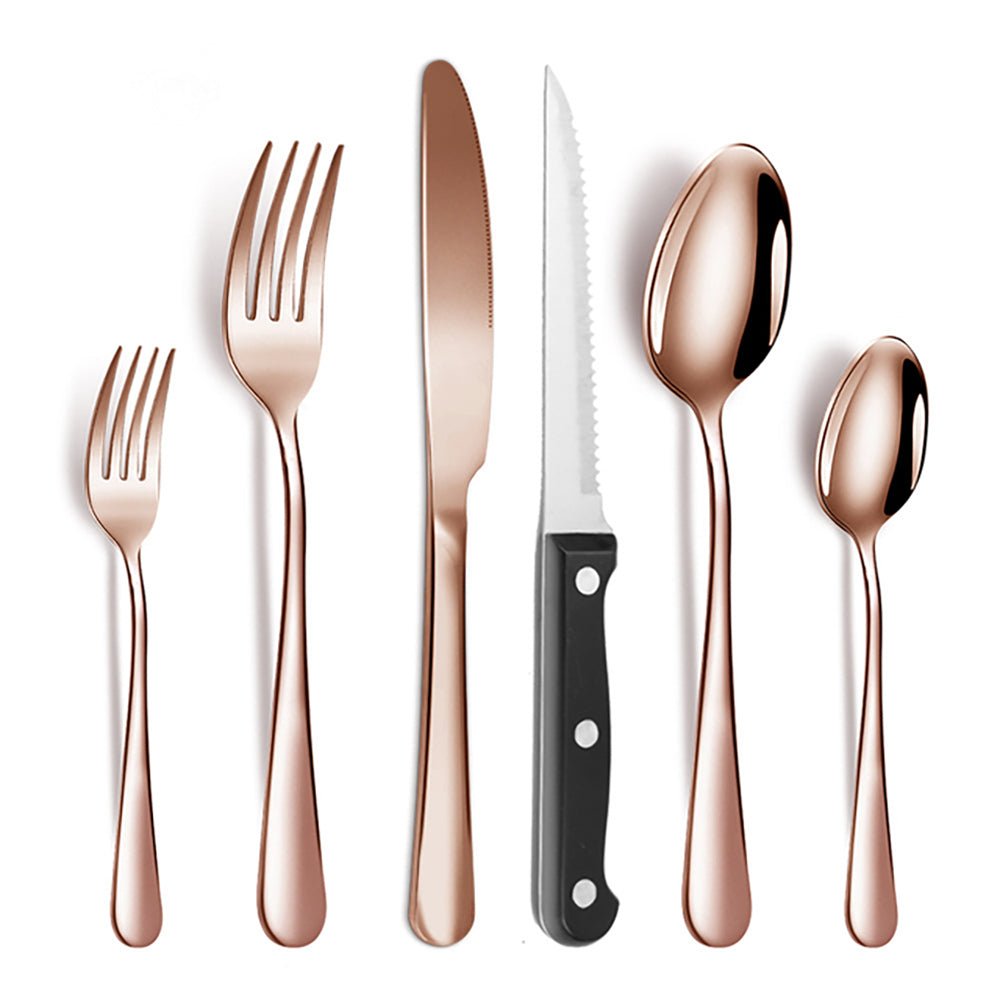 Rose gold flatware set with two forks, two spoons, table knife, and serrated steak knife with black handle on white background