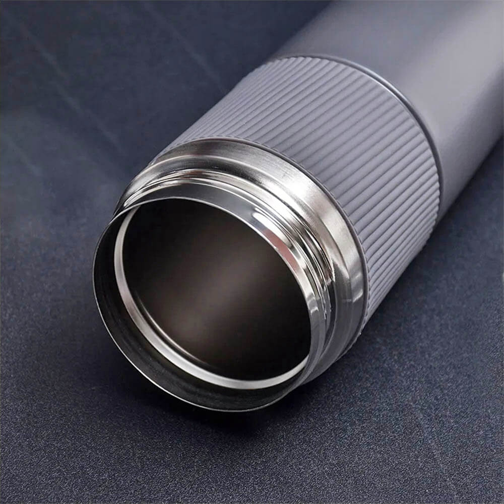 Close-up view of the open mouth of a gray stainless steel coffee tumbler, showing the smooth interior and threaded rim on a dark surface.