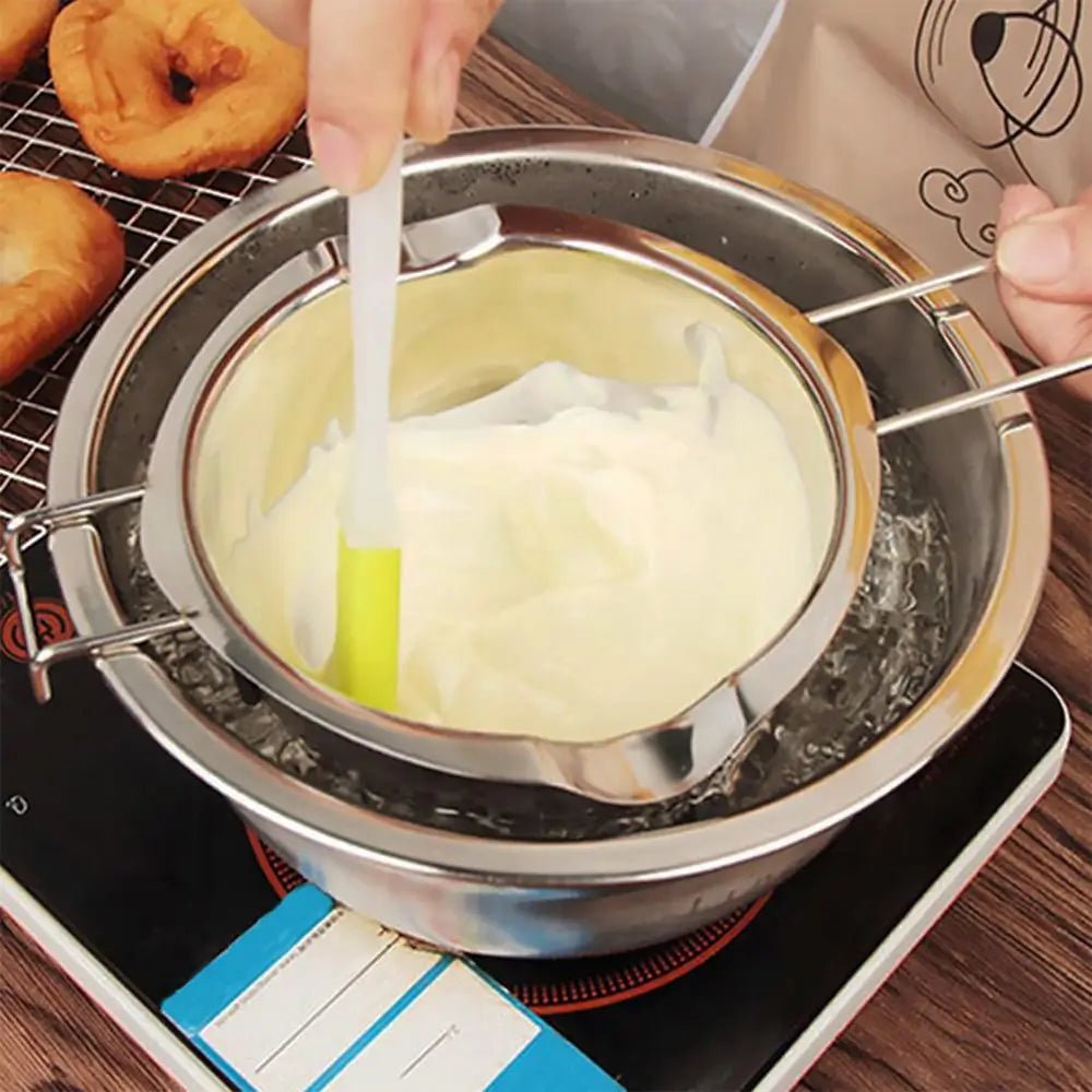 Stainless steel double boiler insert on a pot with a spatula stirring melted white chocolate.