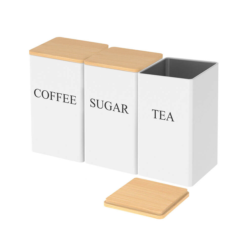 White stainless steel food storage containers labeled COFFEE, SUGAR, and TEA with bamboo lids, one container open with lid beside it.