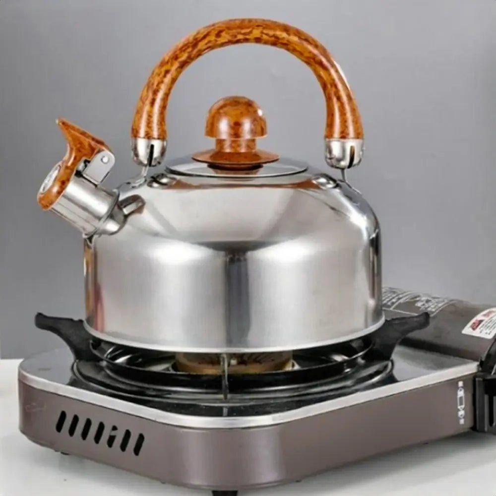 Stainless steel set cookware kettle with wooden handle heating on gas burner, modern compact kitchen setup in background.