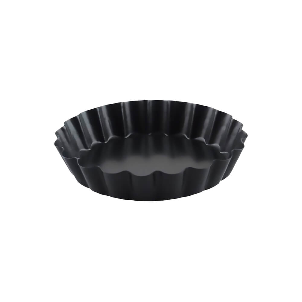 Black fluted tart pan with a removable bottom, placed on a white background.