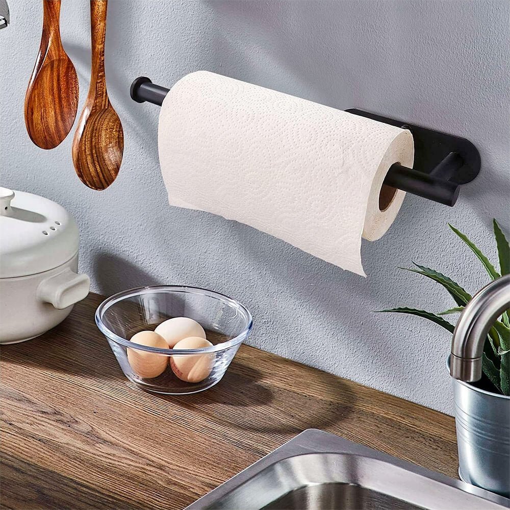 Wall hanging paper towel holder mounted above kitchen counter with black rod holding a white roll near sink and utensils.