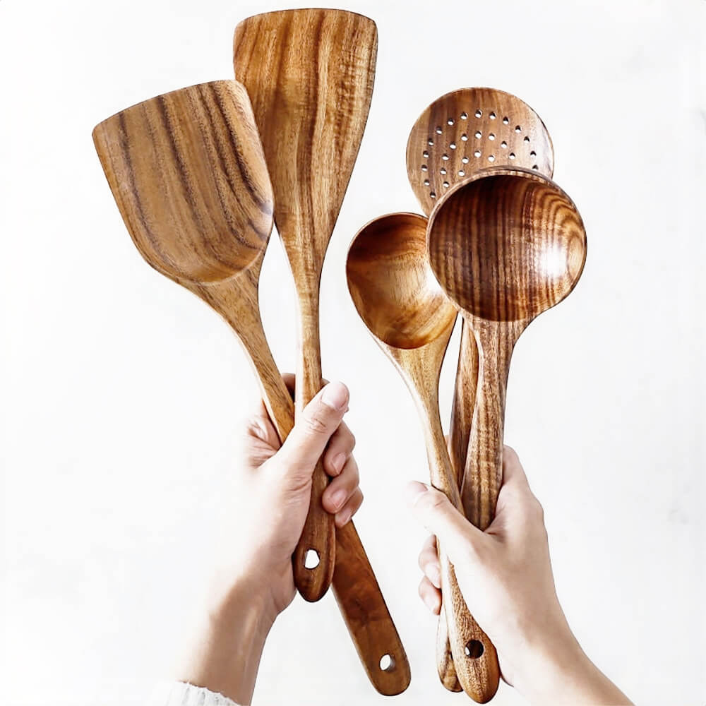 Wood cooking utensils set held in hands, featuring spatulas, spoons, and slotted spoon, ideal for safe non-stick cookware use.