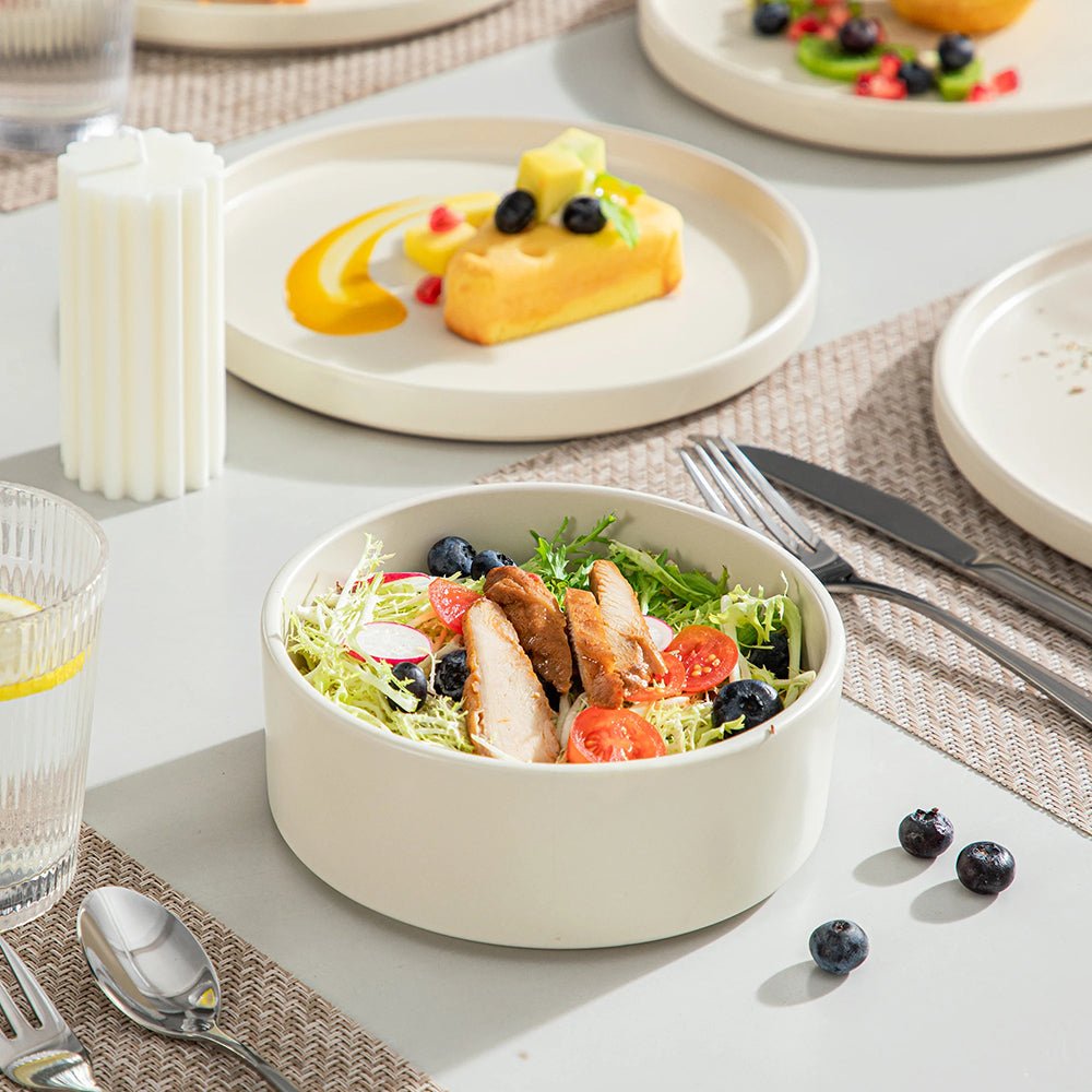 A cereal bowl is at the dining table next to a salad plate, part of the 16-piece stoneware dinnerware set.