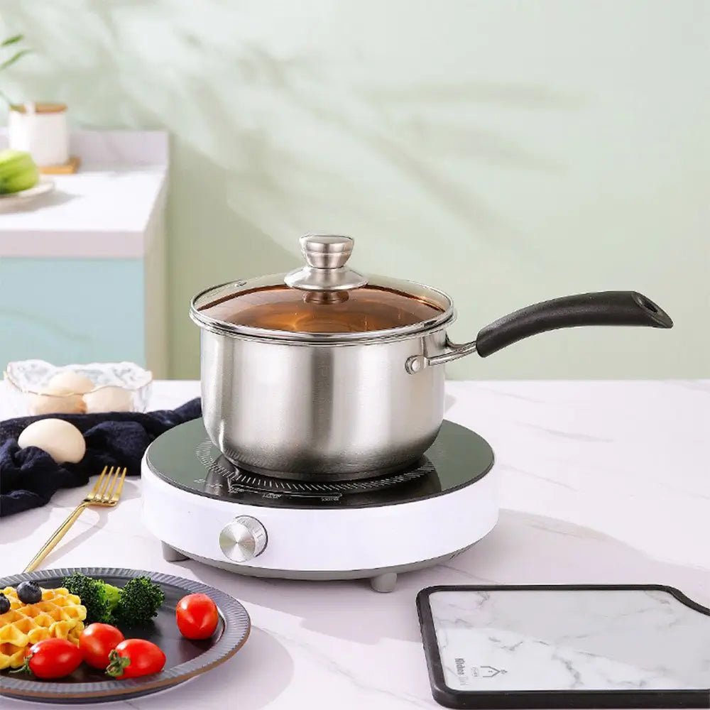 16cm stainless steel saucepan with lid on an electric cooktop, glass lid and black handle, shown in a kitchen setting.
