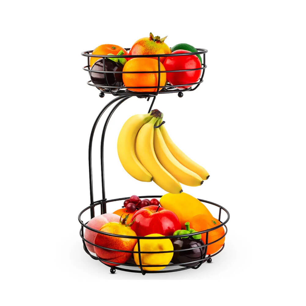 A 2-tier wire fruit basket with a sleek black design on a white background. The lower basket holds apples, oranges, and lemons, while the upper basket features pomegranates and limes. A built-in banana hook suspends a fresh bunch of bananas. 