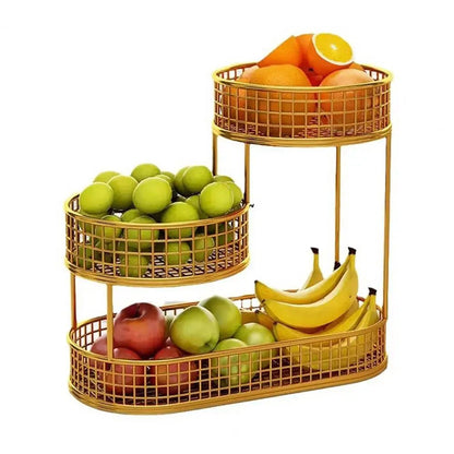 Gold 3 tier fruit basket holding oranges, green apples, red apples, and bananas arranged on three wire mesh tiers.