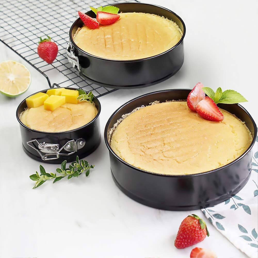 6 inch springform cake pan set with baked cheesecake topped with strawberries and mango cubes.