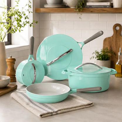 Mint green 7-piece ceramic cookware set featuring a frying pan, saucepan, Dutch oven with lid, and matching lids displayed on a kitchen countertop.