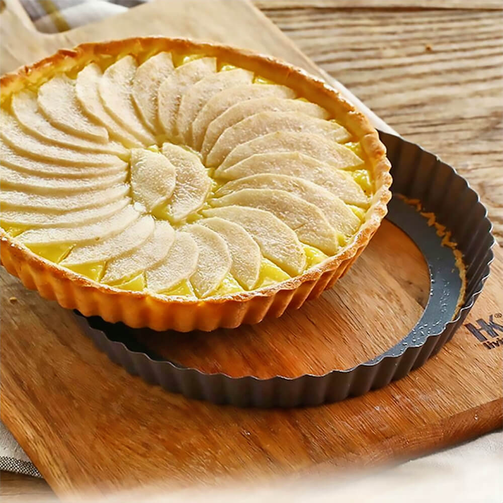 Baked fruit tart on a wooden board, sitting in a fluted tart pan with a removable bottom for easy serving.