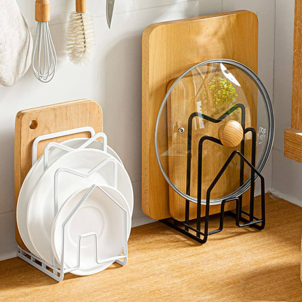 A set of two stylish and functional cutting board racks, one in white and the other in black, showcasing a modern house-shaped design. The white rack neatly holds cutting boards and plates, while the black rack accommodates a wooden cutting board and a glass pot lid. Made from durable metal, these racks are ideal for keeping kitchen essentials organized and accessible. Perfect for those seeking the best cutting board rack for a tidy and efficient kitchen setup.