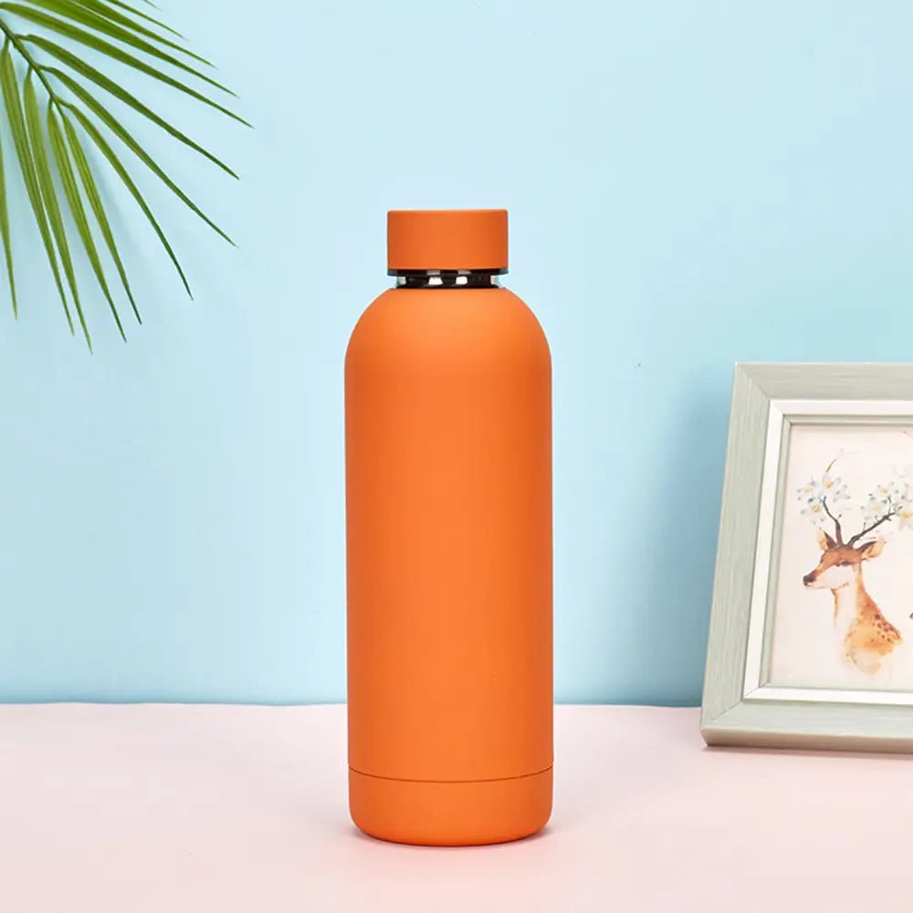 Orange water bottle on a light blue background with a framed picture of a deer.