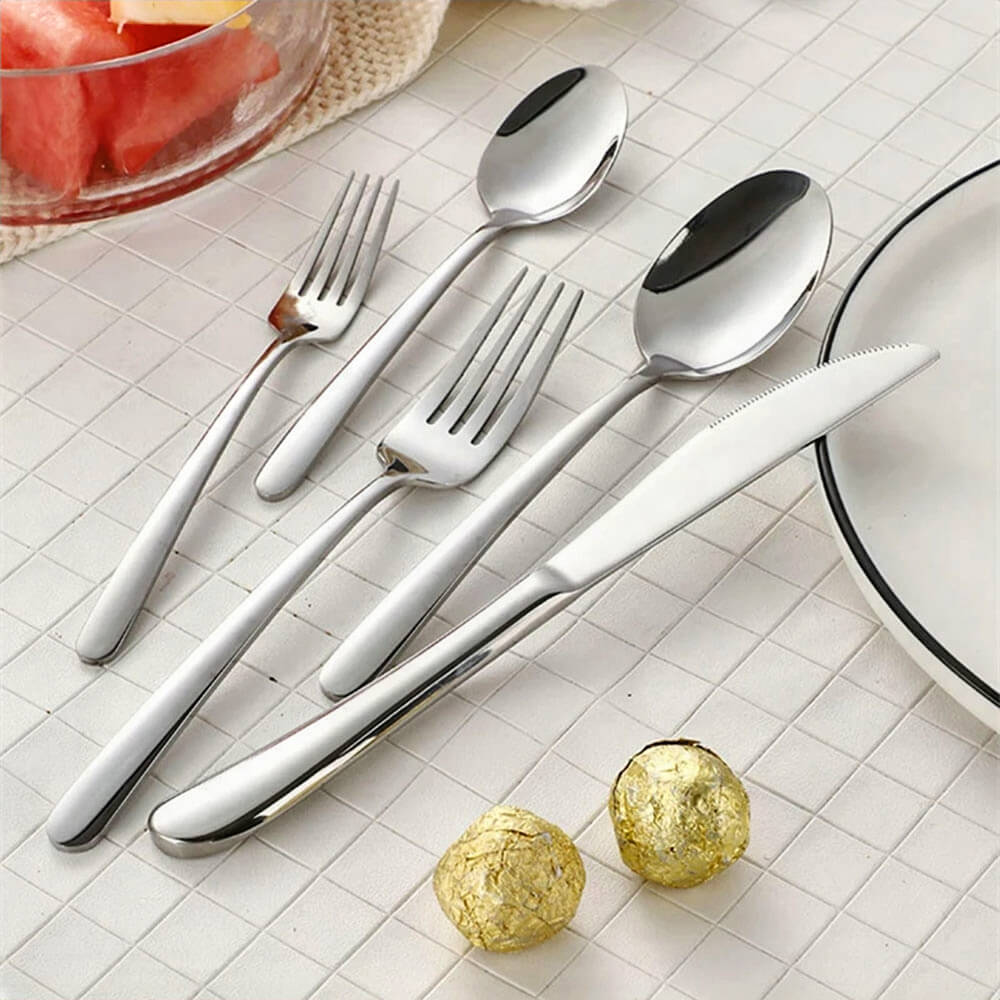 An elegant table setup featuring one of the best-rated silverware sets. The set includes a polished stainless steel knife, forks, and spoons, each with a sleek, modern design and smooth, curved handles. Placed on a textured white surface, the silverware exudes a luxurious yet practical charm, perfect for any dining occasion.