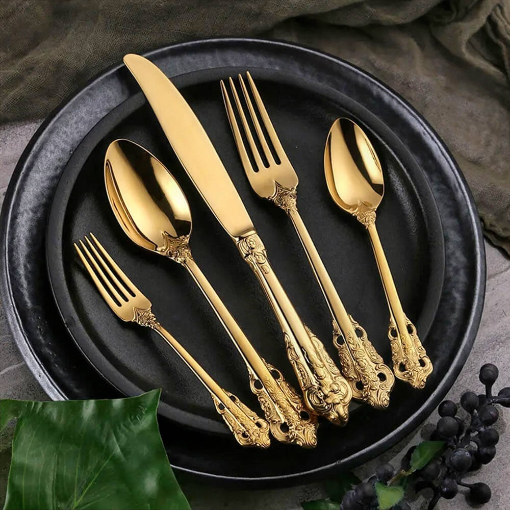 A luxurious stainless steel flatware set with an exquisite gold finish, featuring a knife, fork, spoon, salad fork, and teaspoon. Each piece is meticulously crafted with intricate detailing on the handles, combining durability and elegance to make it one of the best stainless steel flatware sets for any dining occasion.