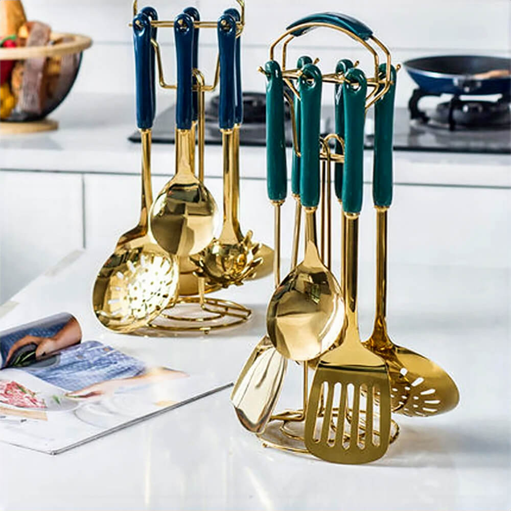 A modern kitchen setup showcasing two sets of premium stainless steel utensils with a luxurious golden finish. Each set features ergonomic dark teal handles and includes essential cooking tools such as ladles, slotted spoons, and spatulas, neatly organized on matching golden stands. Ideal for both functionality and style, these utensils elevate any kitchen with their elegant design.