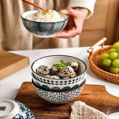 A woman holds a bowl of fluffy rice and another filled with creamy cheese, both elegantly presented in decorative ceramic bowls on the table.