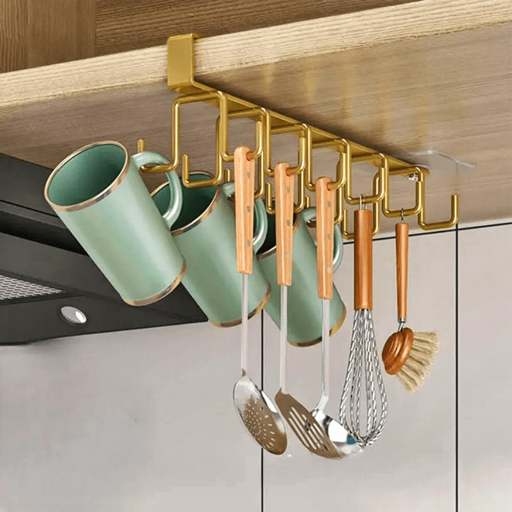 Elegant cabinet rack organizer mounted under a wooden shelf, featuring gold hooks holding green mugs and wooden-handled kitchen utensils, creating a tidy and stylish kitchen space.