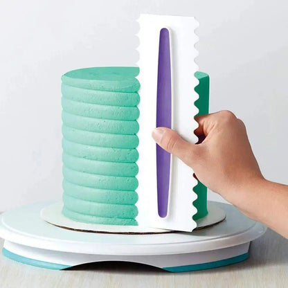 A hand uses cake icing combs on a round cake with teal frosting to create evenly spaced horizontal ridges around the sides.