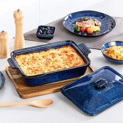 Blue porcelain casserole dish filled with baked lasagna placed on a wooden board, with its matching lid and tableware nearby.