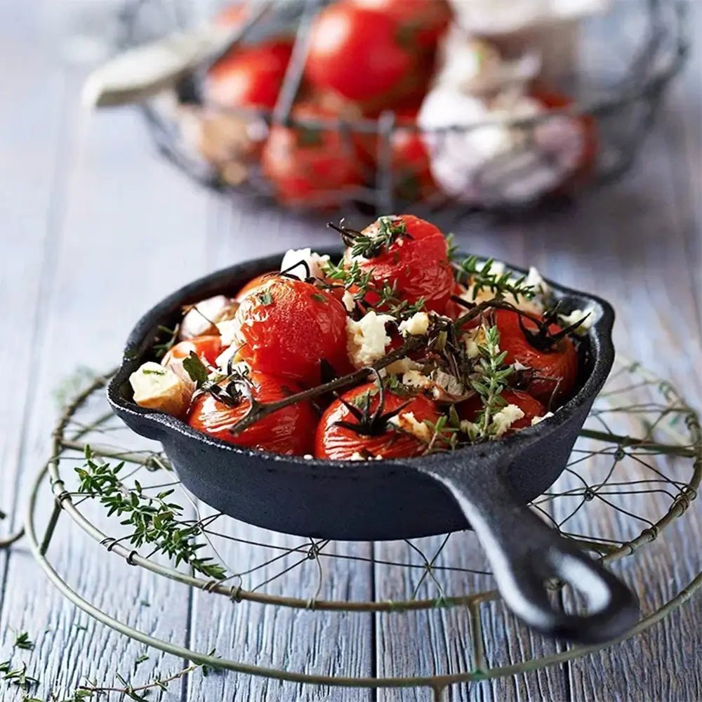 Skillet with roasted tomatoes and herbs on a rustic wooden surface