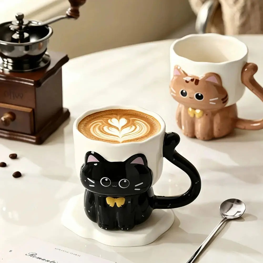Cat-shaped coffee mugs with a cappuccino on a table with a coffee grinder and spoon.