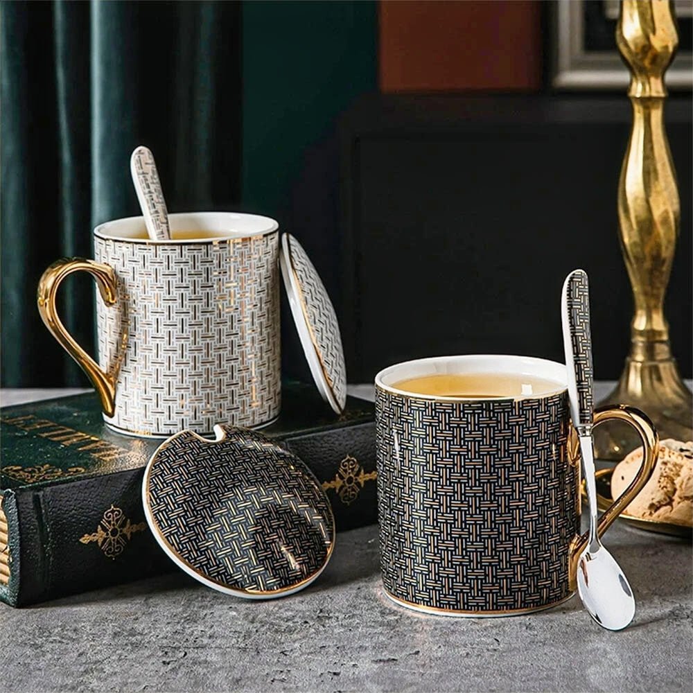 Ceramic coffee mug with a ceramic lid, featuring a geometric pattern and gold accents, paired with a matching spoon.