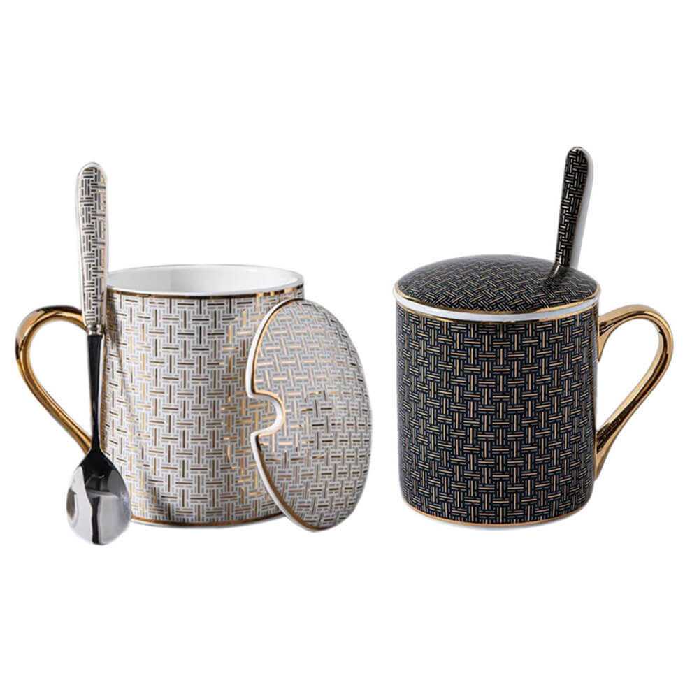 Set of ceramic coffee mugs with lids on a white background, featuring geometric patterns, gold accents, and matching spoons.