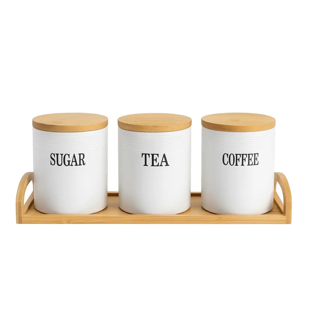 Ceramic tea coffee sugar canisters with bamboo lids arranged on a wooden tray against a white background.
