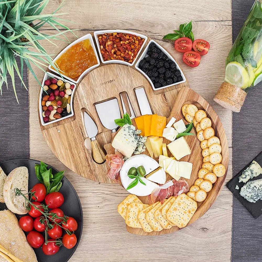Cheese knives and board set with wooden platter, ceramic bowls of nuts, berries and spreads, assorted cheeses, crackers and meats.