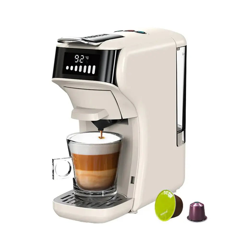White coffee pod machine with digital display brewing cappuccino into a glass cup, two capsules placed beside on white background.