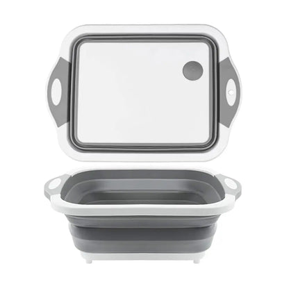 Gray and white collapsible cutting board shown expanded, featuring a cutting surface and deep basin for rinsing or food prep.
