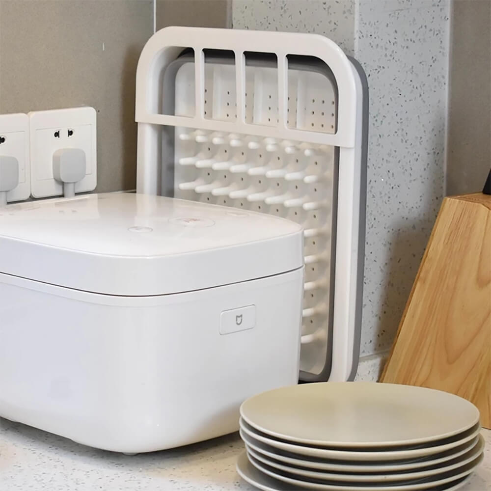 Space-saving collapsing dish rack in white and gray, shown folded neatly behind kitchen appliances, ideal for compact kitchens and organized storage.