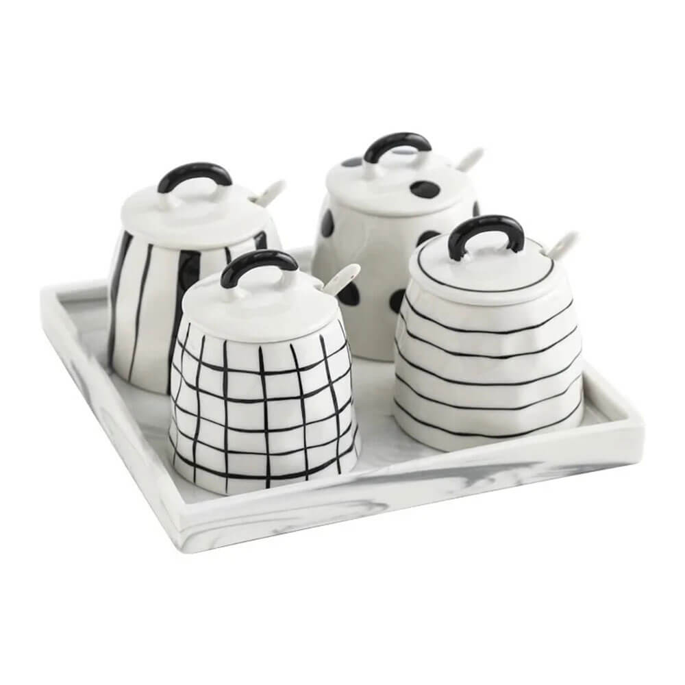 Set of four ceramic condiment containers with black and white patterns, matching lids, ceramic spoons, and a rectangular marble-patterned tray.