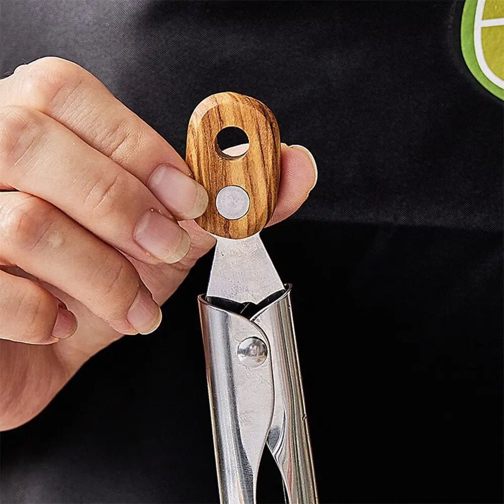 Hand holding a wooden-handled kitchen tool against a black background.