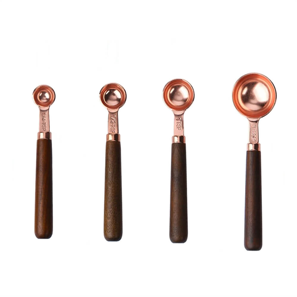 A sleek set of copper measuring spoons featuring polished copper-plated bowls and dark wooden handles. The set includes four different sizes, each engraved with measurements for easy readability, combining timeless elegance with practical functionality. Perfect for enhancing any kitchen setup.