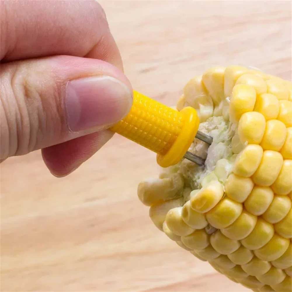 Hand using corn holders for corn on the cob to safely grip and enjoy hot, buttery corn without the mess.