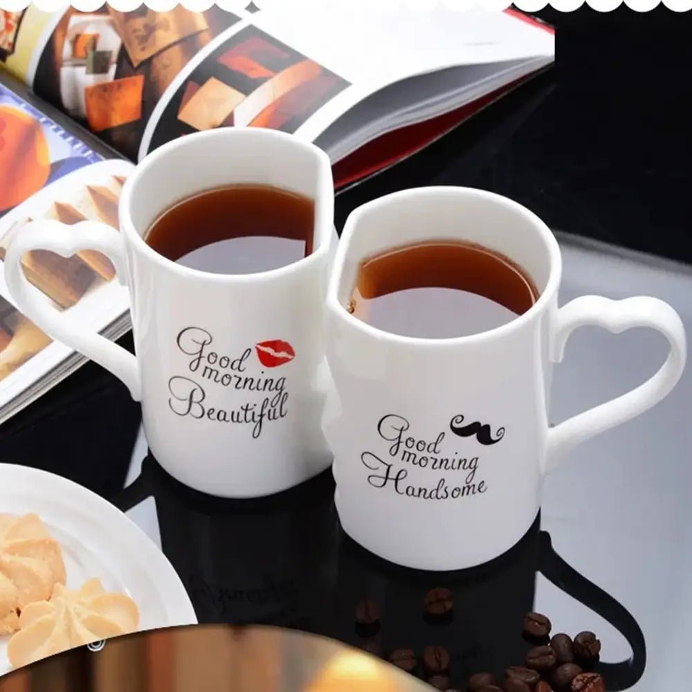 Two white mugs with humorous text designs on a table with coffee and snacks.