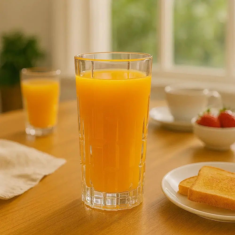 Highball glass of orange juice on a wooden table with toast and strawberries.